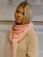 Woman wearing a pink scarf standing in front of a wall with biographical posters.