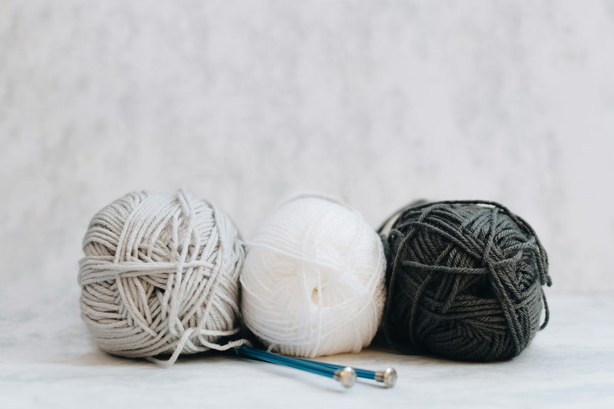 White, grey and black yarn with knitting needles
